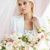 How do you wear layered necklaces; a women wearing Abbott Lyon’s gold layered necklaces surrounded by flowers.